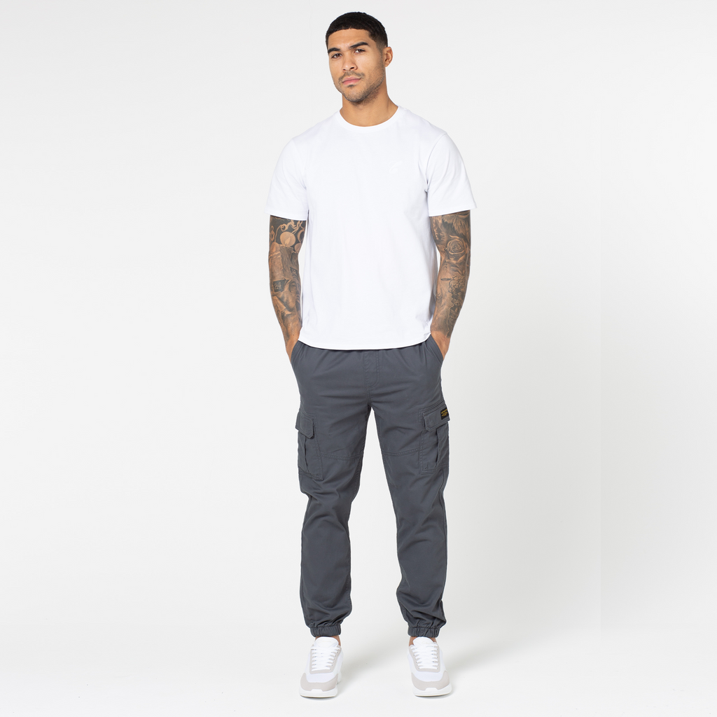 Men's charcoal utility cargo pants styled with white and grey trainers and white short sleeve top