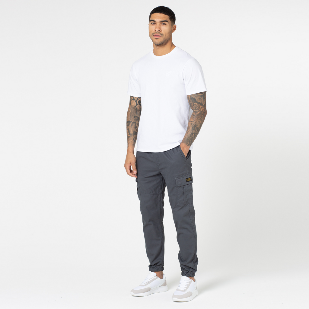 Model wearing dark grey cargo pants with white top and white trainers