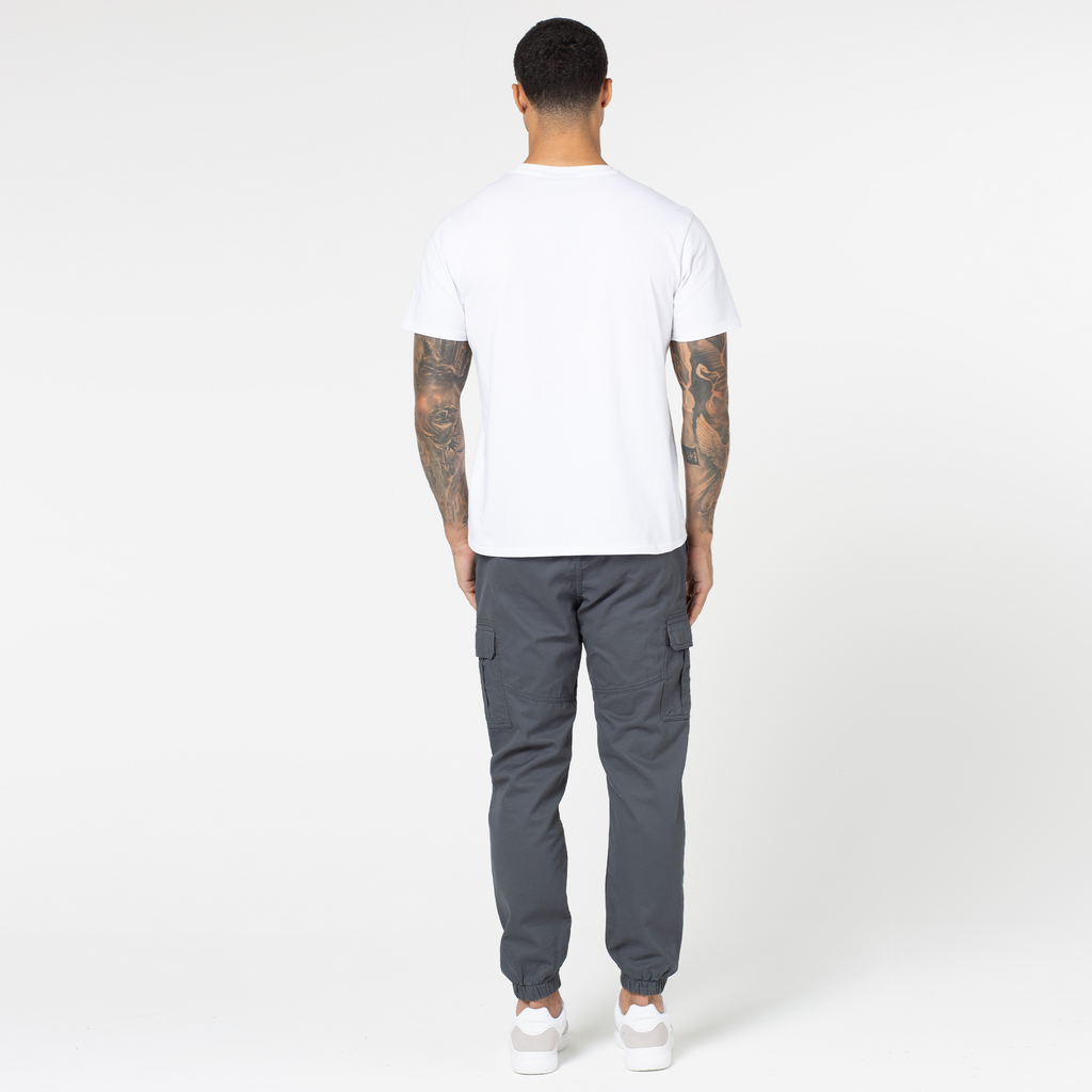 Back profile view of cargo pants in dark grey paired with trainers and white top