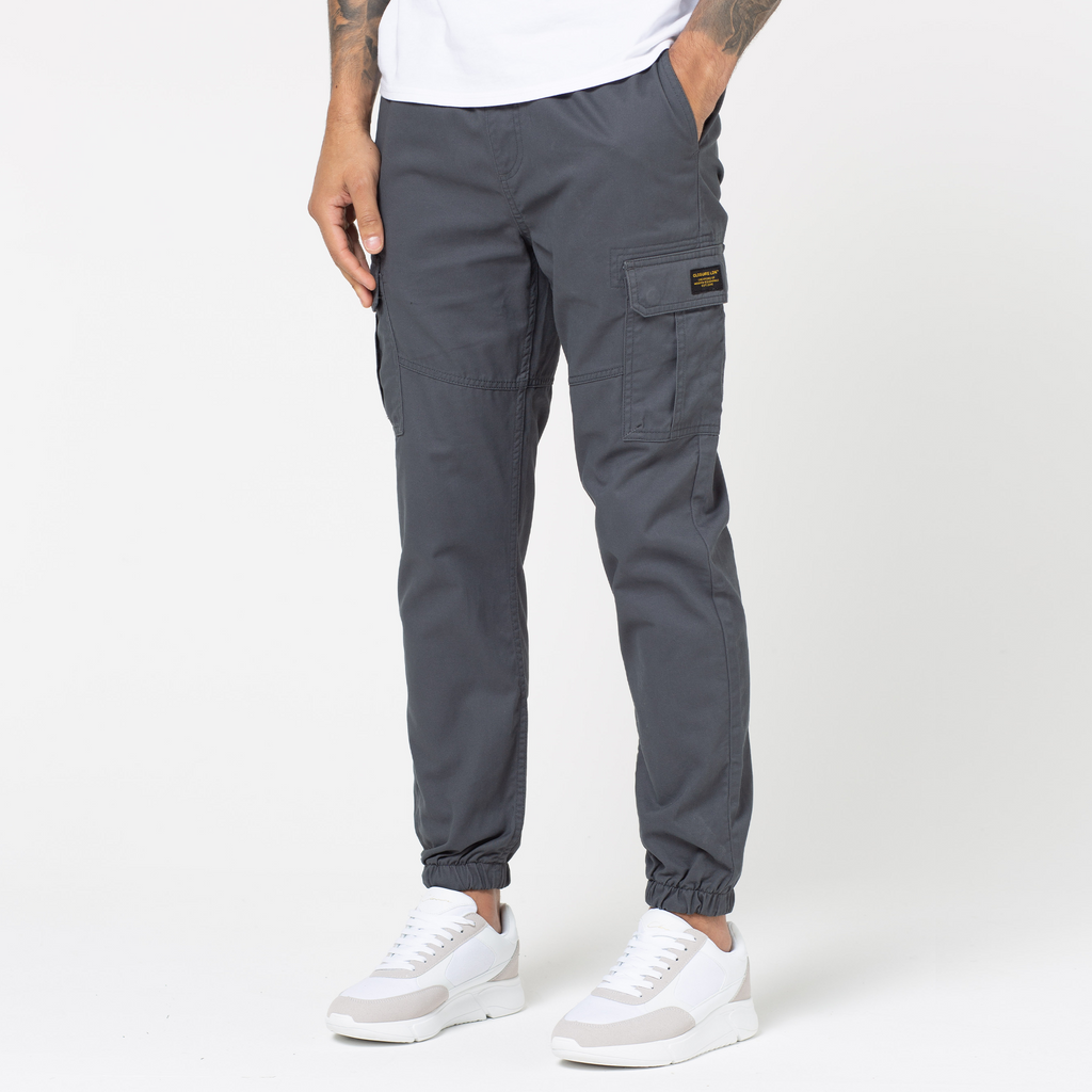 Men's utility trousers in charcoal grey cuffed feature paired with white trainers